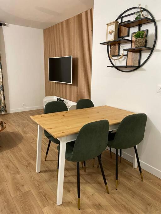 a dining room table with green chairs and a television at Magnifique appartement de 4 chambres 8 personnes max à 20 minutes de Paris in Antony