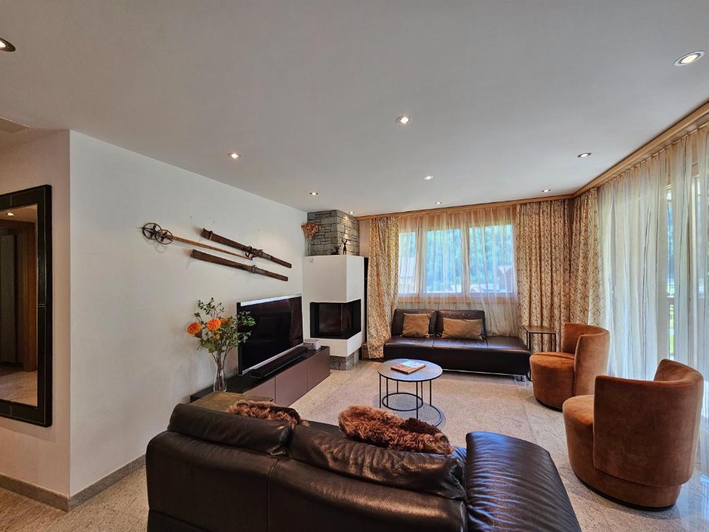 uma sala de estar com um sofá de couro e cadeiras em Aramis Lodge em Saas-Fee