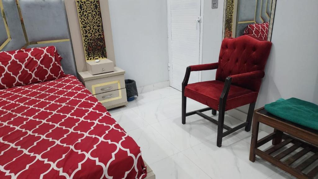 a bedroom with a red bed and a red chair at The Karachi Guest House in Karachi