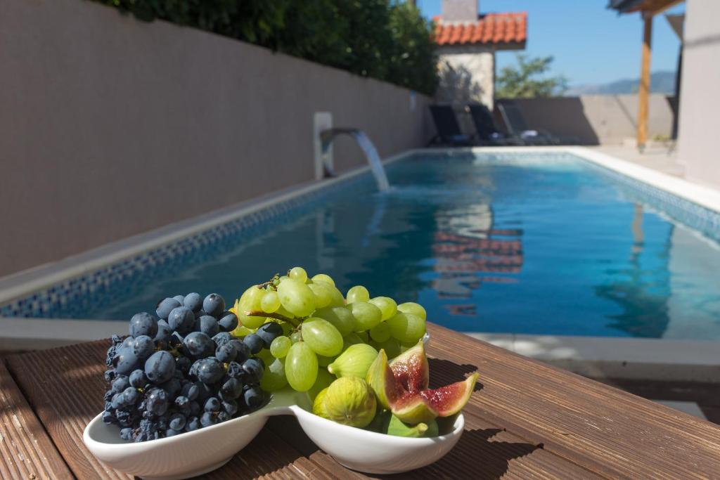 due ciotole di frutta su un tavolo accanto alla piscina di LIFE - NEW and LUXURY holiday house a Kaštela (Castelli)