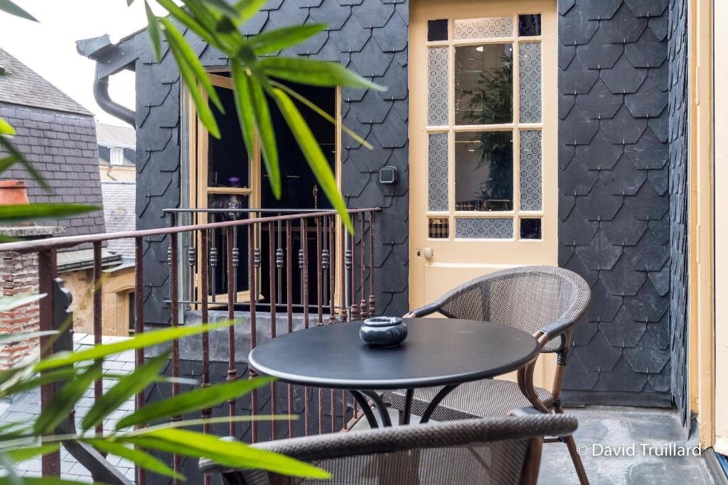 een tafel en stoelen op een balkon met een deur bij Suites Mana- Le Boudoir Art Déco 4* Place Ducale Parking inclus in Charleville-Mézières