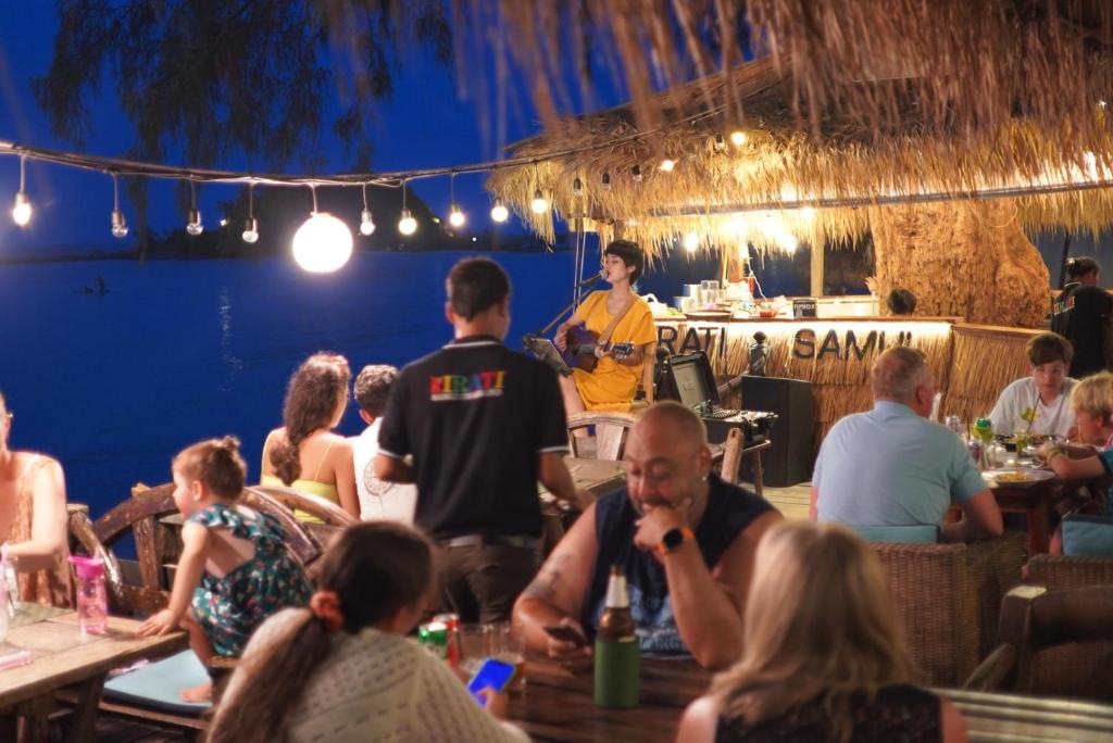 een groep mensen die aan tafel zitten in een restaurant bij Kirati Beach Resort in Choeng Mon Beach