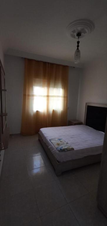 ein Schlafzimmer mit einem Bett und einem Fenster mit einem Vorhang in der Unterkunft Dar zman in Kelibia