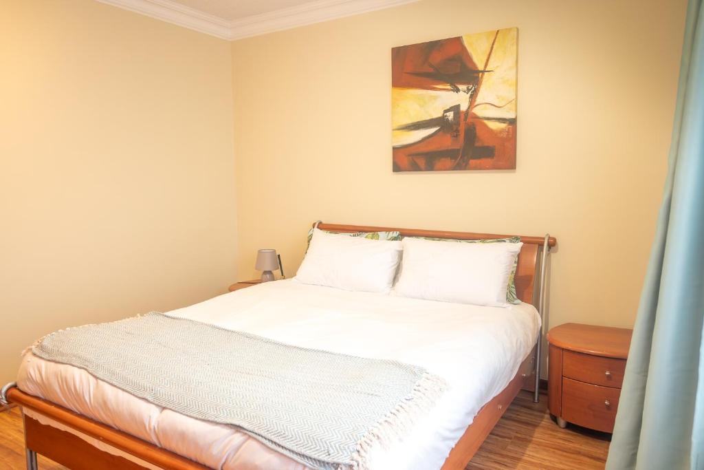 a bedroom with a bed with white sheets and a painting at Premium Getaway @ la Bella Costa in Pretoria