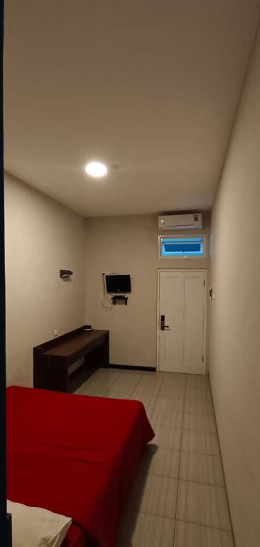 a room with a red bed and a desk in it at Bromo Family Guest House in Kepanjen