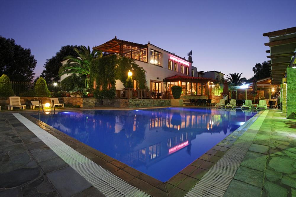 a large swimming pool in front of a house at Castello Rosso Hotel in Nea Stira