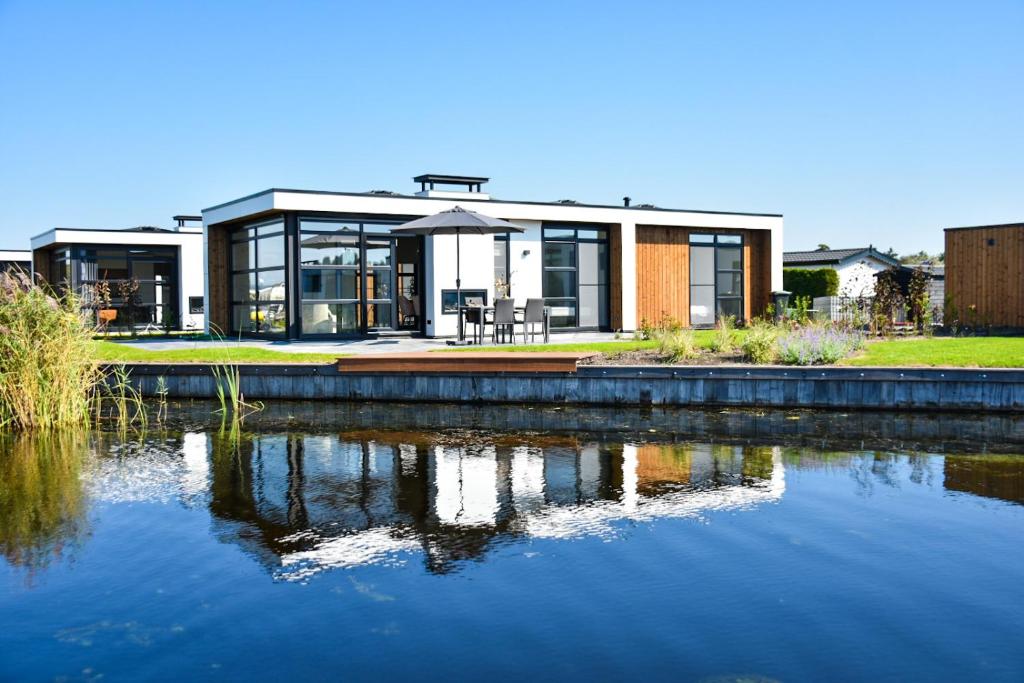 una casa con un lago delante de ella en MarinaPark Residentie Nieuw Loosdrecht, en Loosdrecht