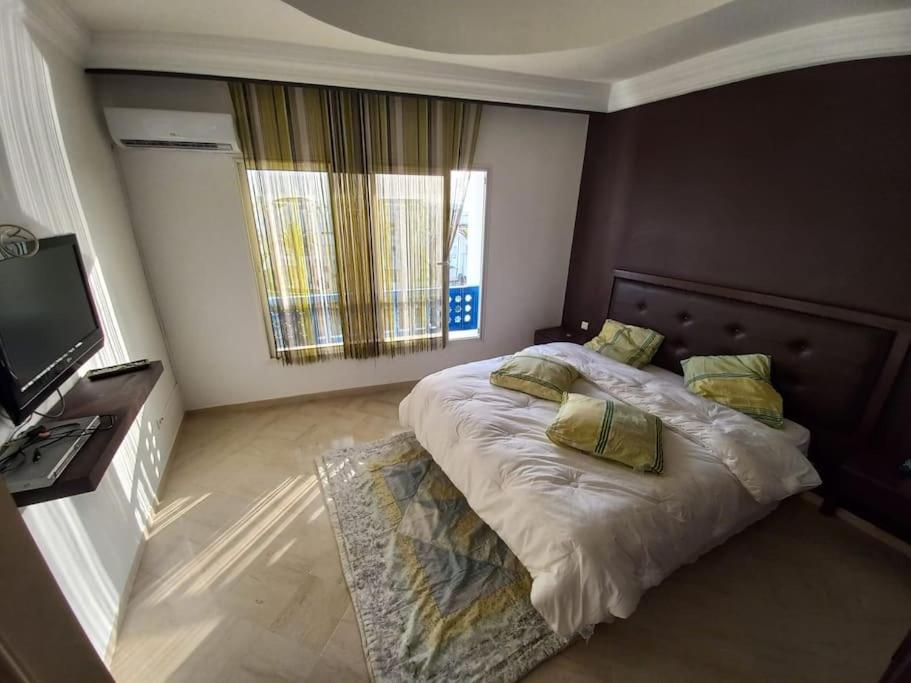 a bedroom with a large bed and a television at Appartement de luxe au coeur de la marina Hammamet in Hammamet