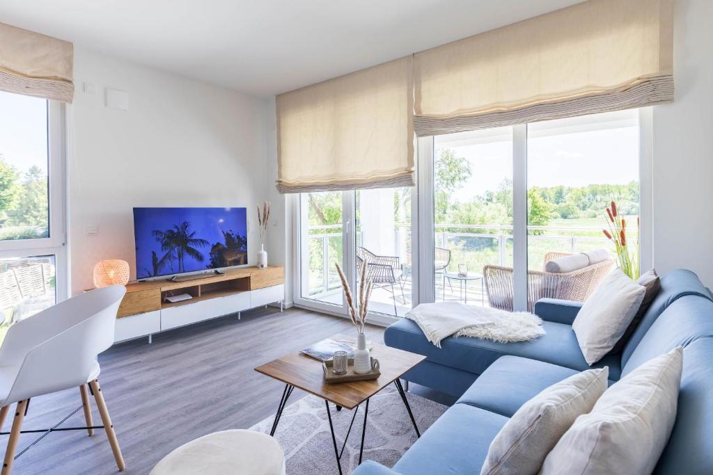 ein Wohnzimmer mit einem blauen Sofa und einem TV in der Unterkunft Weiße Villen "das Meeresloft" in Boltenhagen