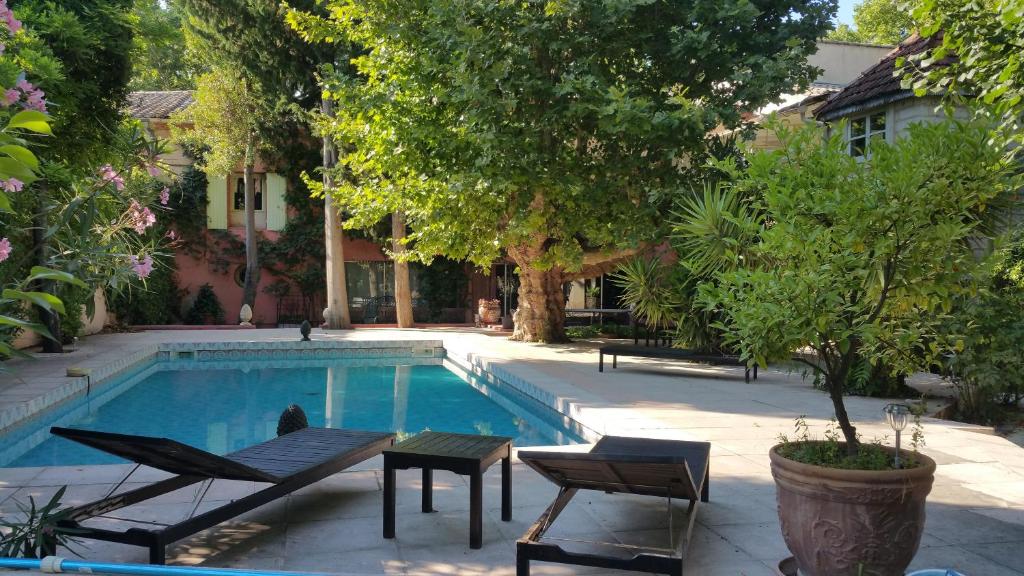 einen Pool mit Stühlen und einem Tisch neben einem Haus in der Unterkunft Maison Avec Piscine, Tennis, Sauna in Marsillargues