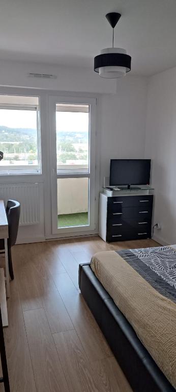 a bedroom with a bed and a tv and two windows at Chambre privé avec loggia chez l'habitant in Champigneulles