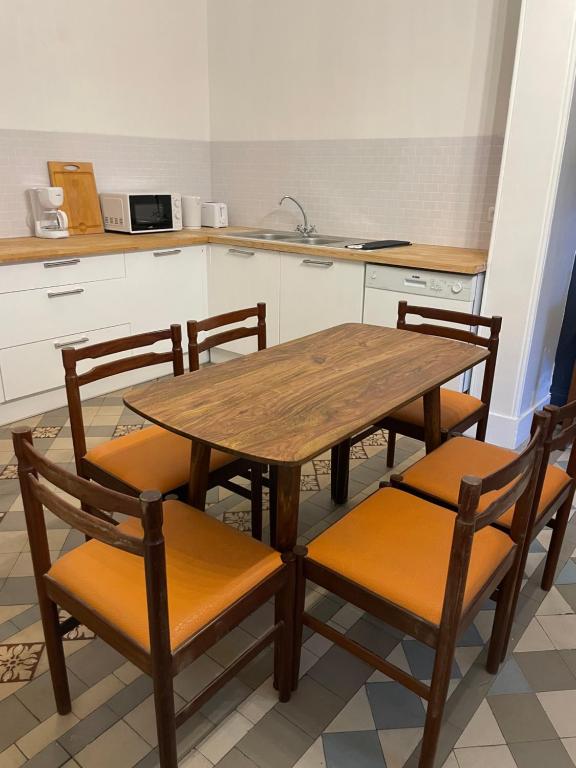 une cuisine avec une table en bois et quatre chaises dans l'établissement La Grande Dame - T4 - Clim, à Perpignan