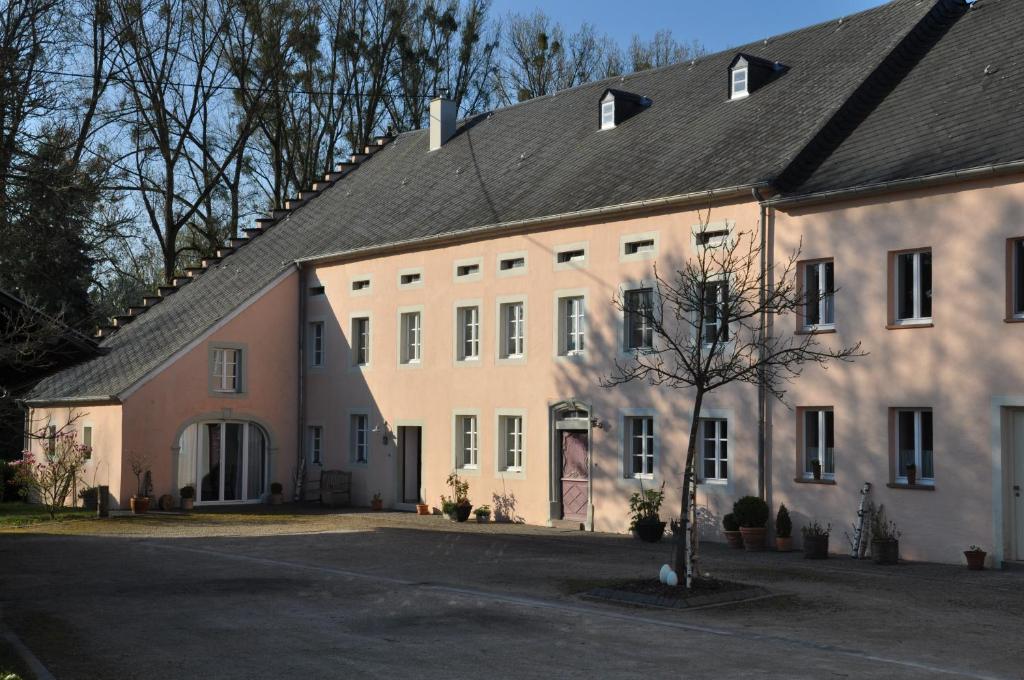 ein großes weißes Gebäude mit schwarzem Dach in der Unterkunft Alte Schmiede in denkmalgeschützter Hofanlage in Messerich