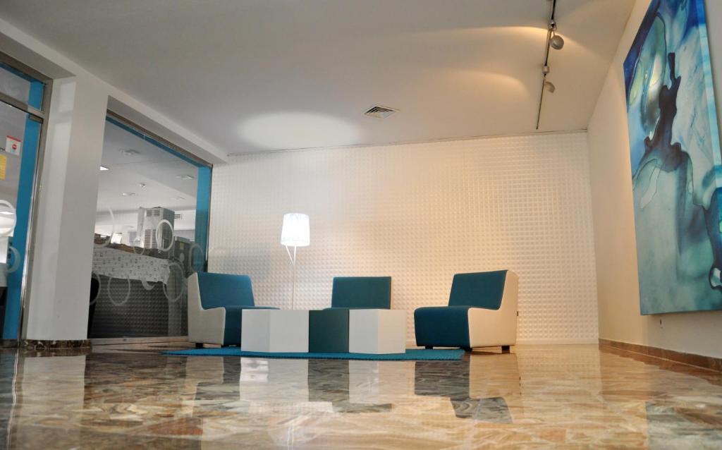 a lobby with blue chairs and a wall at Hotel Castilla Alicante in Alicante