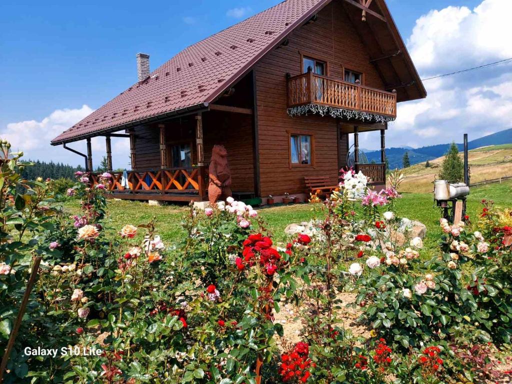 a wooden house with a balcony in a field of flowers at Карпатська Модринка in Vorokhta
