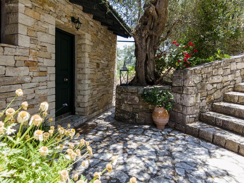 a brick building with a black door and a tree at Adamantia Studio S2 in Gaios