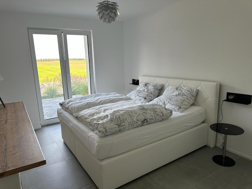 ein weißes Bett in einem weißen Zimmer mit Fenster in der Unterkunft Hof Busen Landhaus Ap. in Mönchengladbach