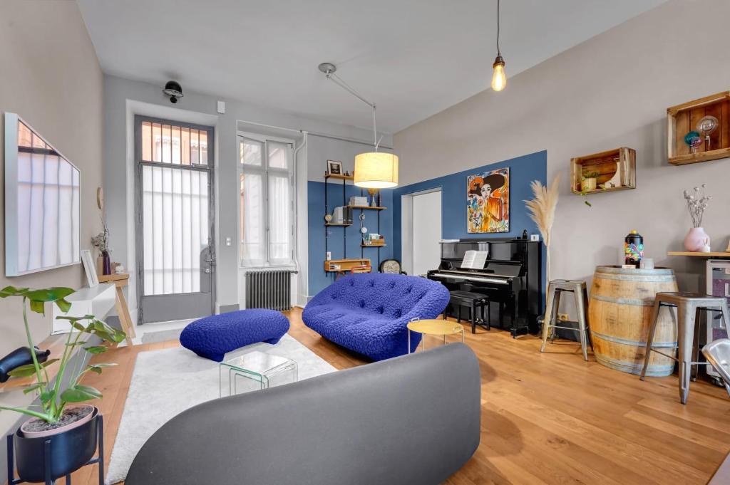 een woonkamer met blauwe stoelen en een piano bij Bleu du Maine - Elegant T3 avec terrasse in Toulouse