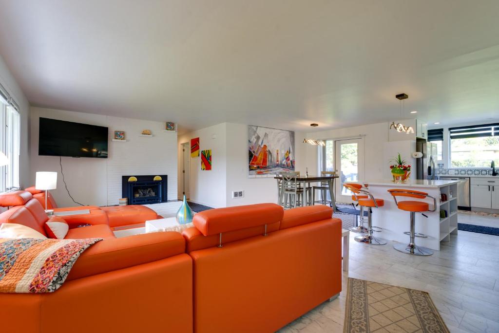 a living room with an orange couch and a kitchen at Rustic Retreat in Spokane Valley with Cozy Fireplace in Spokane Valley