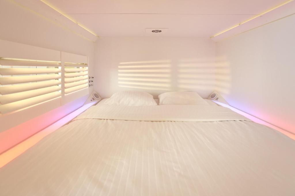 a white bed in a room with a window at CityHub Rotterdam in Rotterdam