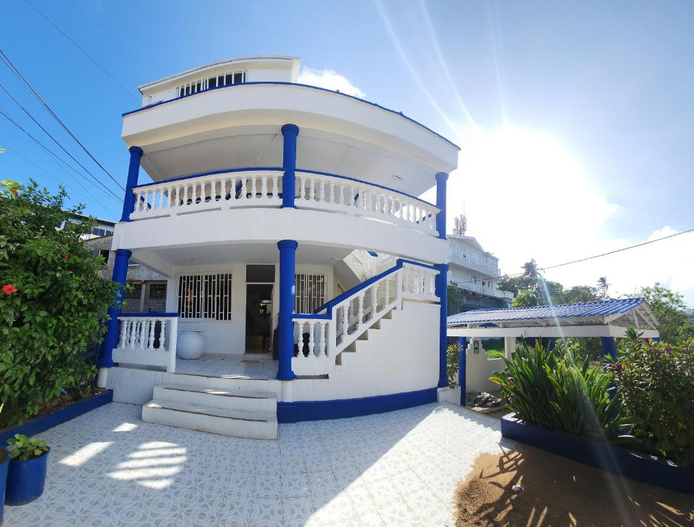 Una gran casa blanca con columnas azules y escaleras en Apartamentos SurOeste en San Andrés