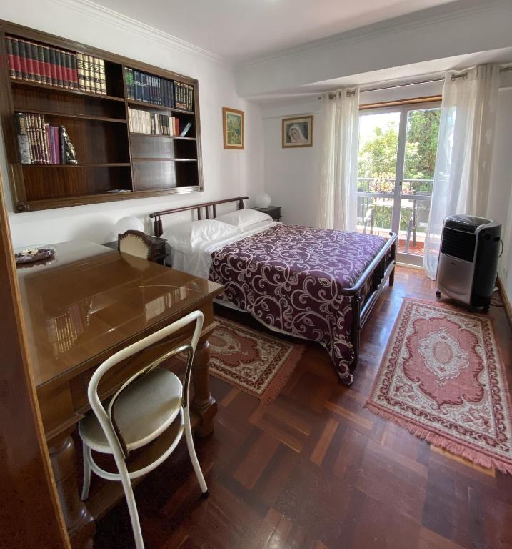 a bedroom with a bed and a desk and a window at Simbiose in Carcavelos