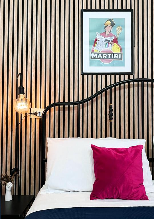 cama con almohada roja y póster en la pared en Fifteen Apartment, en Nápoles
