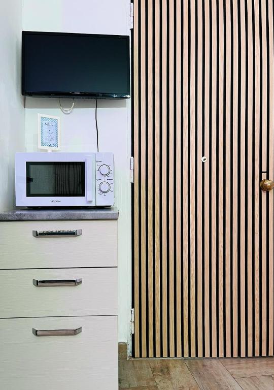 kuchenka mikrofalowa na ladzie obok drewnianych ogrodzeń w obiekcie Fifteen Apartment w mieście Neapol
