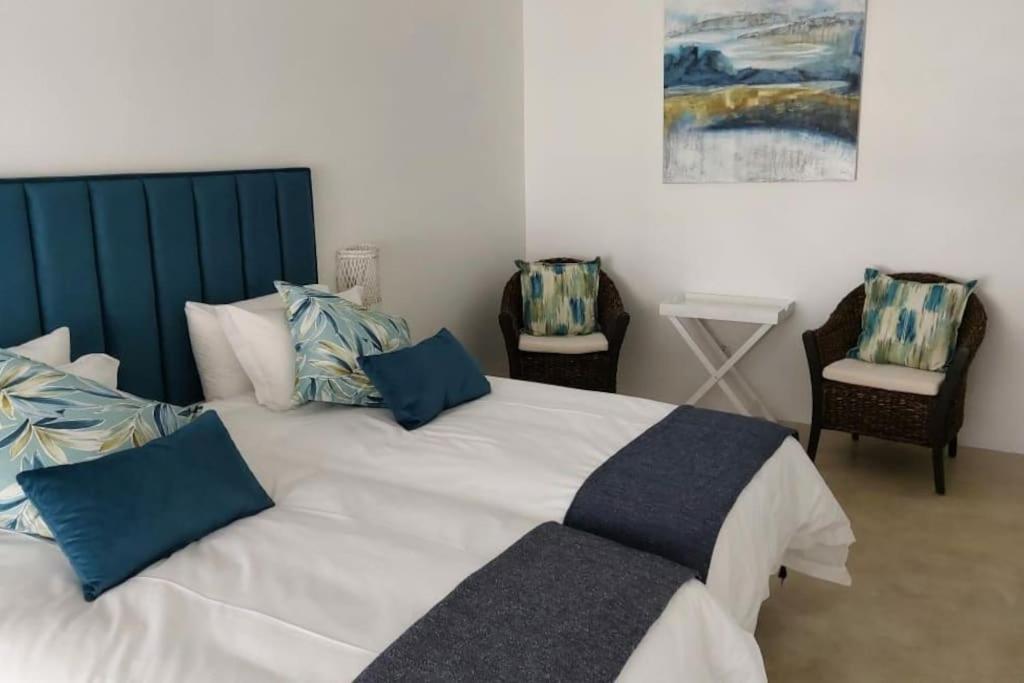 1 dormitorio con 1 cama blanca grande con almohadas azules en Tropicana Guesthouse en Ponta do Ouro