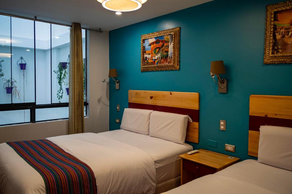 una camera con due letti e una parete blu di HOTEL LUZ GARDEN a Machu Picchu