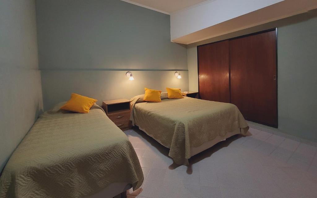 2 camas en una habitación de hotel con almohadas amarillas en Alquileres Grutenses en Las Grutas