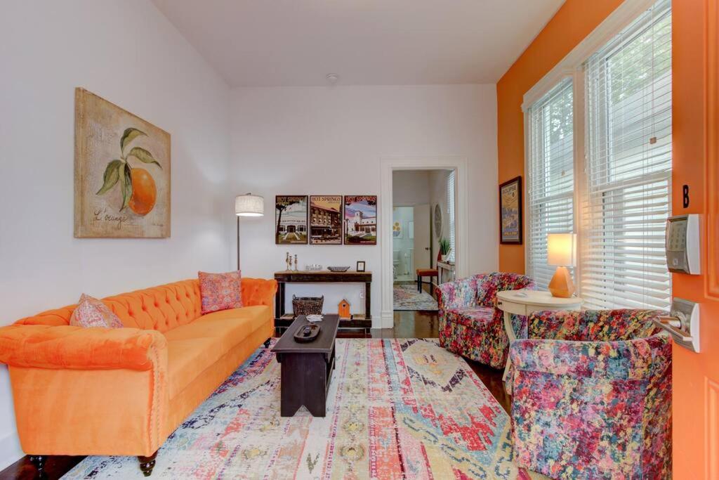 a living room with an orange couch and a table at Tangerine Bungalow Downtown Hot Springs in Hot Springs