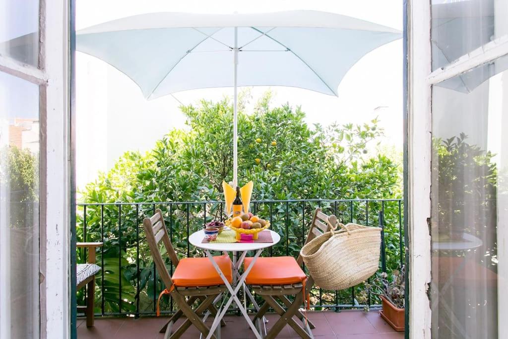 a table with an umbrella on a balcony at Principe Real Orange tree w/ view 3 bedrooms flat! in Lisbon