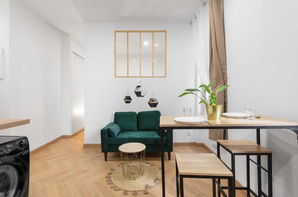 a living room with a green chair and a table at Le Verdoyant - T2 moderne - proche Gare in Toulouse