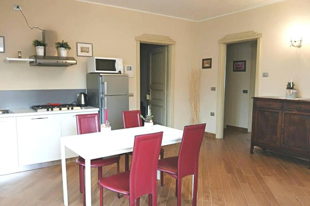 a kitchen with a white table and red chairs at CIAREI alloggio in villa prima collina biellese in Tollegno