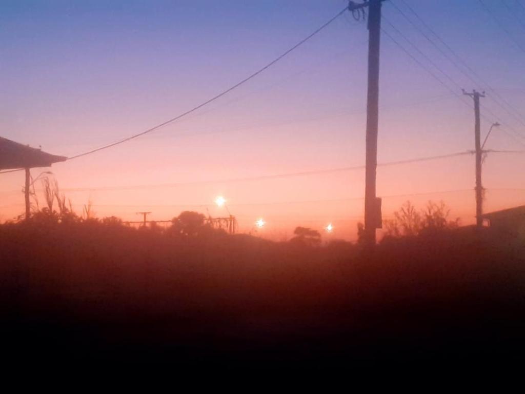 ein Sonnenuntergang auf einem Feld mit einigen Strommasten in der Unterkunft Sa-Ra's vakantiehuis in Paramaribo