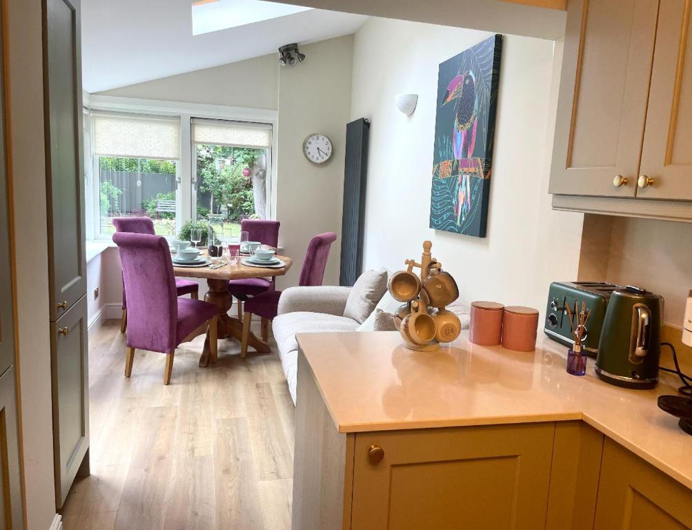 a kitchen and living room with a table and purple chairs at Fashionable Chic Townhouse in D4 in Dublin