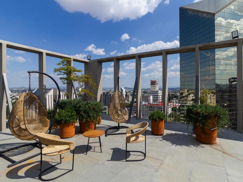 a balcony with chairs and tables on top of a building at Tribu Chapultepec 67 in Guadalajara