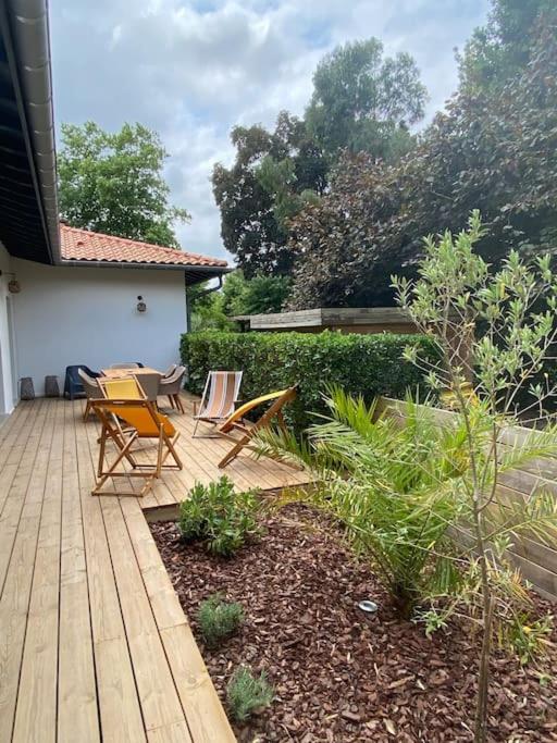 une terrasse en bois avec 2 chaises et une table. dans l'établissement Maison cocooning proche plages, à Soustons