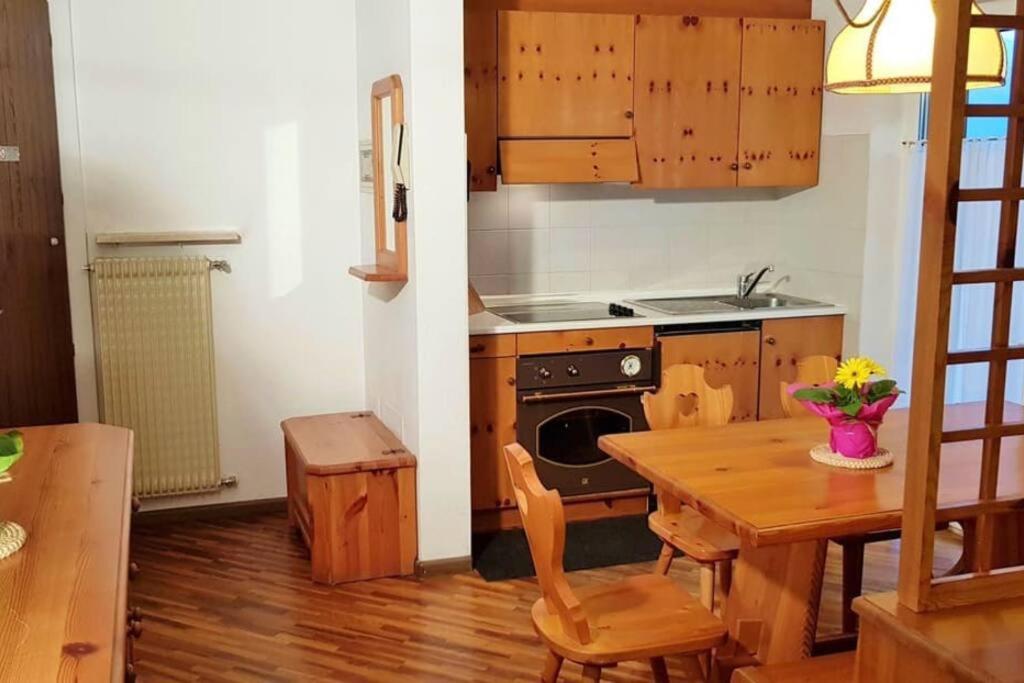 eine Küche mit einem Tisch, einem Herd, einem Tisch und Stühlen in der Unterkunft Casa Ava Cavalese in Cavalese