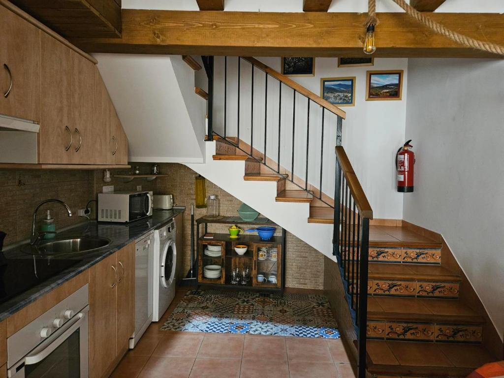 cocina con escalera, fregadero y fogones en El Nido, Casa Rural, en Casas del Castañar