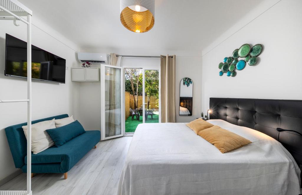 a bedroom with a bed and a blue couch at Bord de mer- Studio avec jardin in Roquebrune-Cap-Martin
