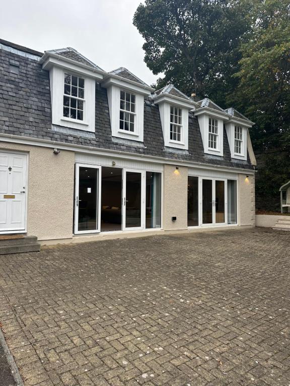 ein großes Haus mit weißen Fenstern und einer Auffahrt in der Unterkunft Cameron Coach House Modern Property in Murrayfield Edinburgh in Edinburgh