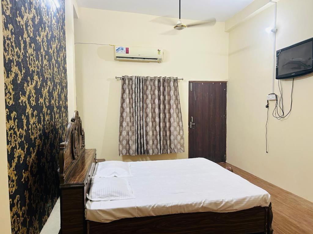 a small bedroom with a bed and a television at RN Residency in Varanasi