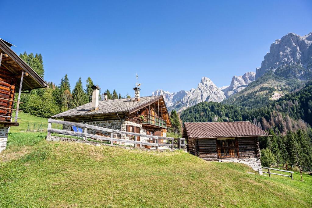 une maison sur une colline avec des montagnes en arrière-plan dans l'établissement Baita Valmesta, à Fiera di Primiero