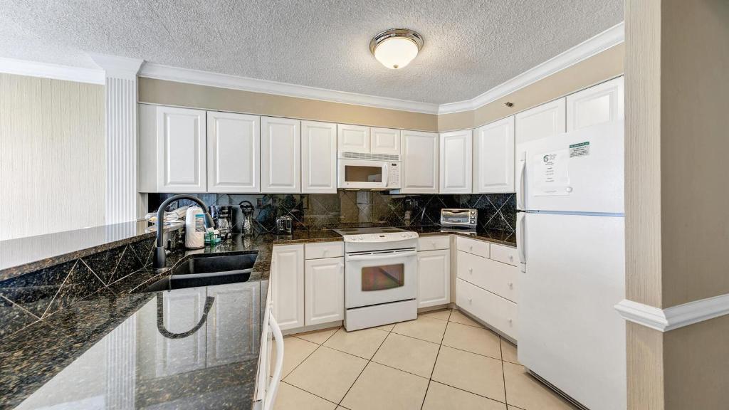 a kitchen with white cabinets and a white refrigerator at Destin on the Gulf 607 - Updated Gulf Front Property at Destin on the Gulf in Destin