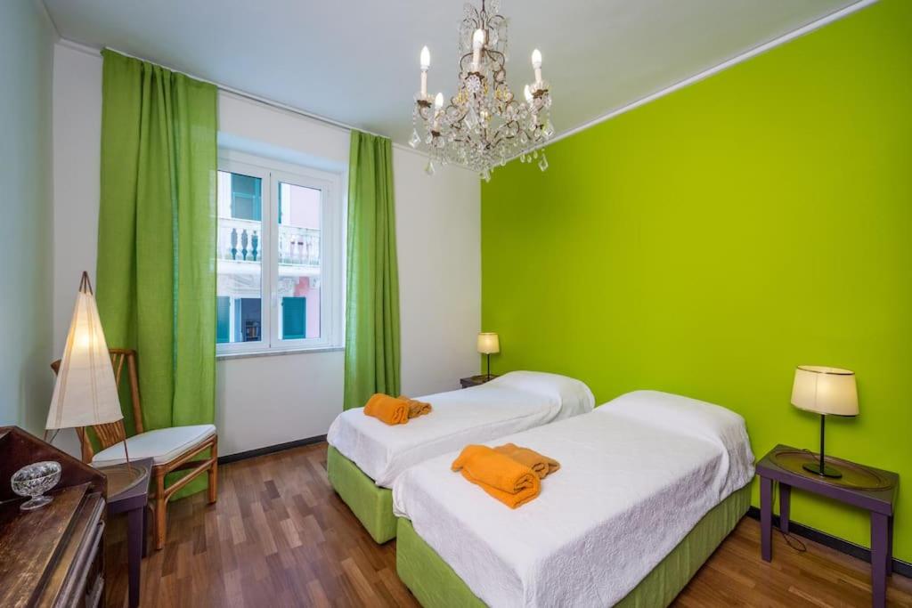 een groene kamer met 2 bedden en een kroonluchter bij Casamati Flexyrent in Rapallo