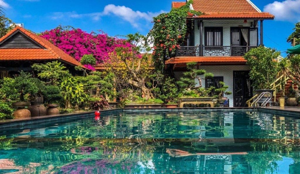 a house with a swimming pool in front of a house at Betel Garden Villa in Hoi An
