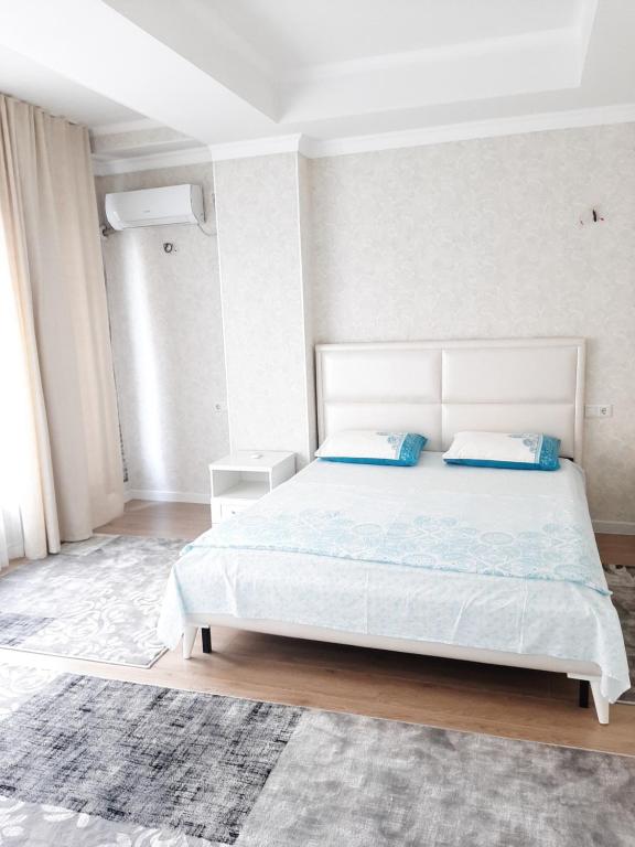 ein Schlafzimmer mit einem weißen Bett mit blauen Kissen in der Unterkunft Comfortable apartment in Bischkek