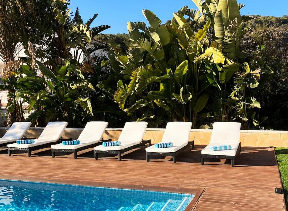 - une rangée de chaises longues à côté de la piscine dans l'établissement Tranquil and spacious 5 bedroom family villa, à Sant Pere de Ribes